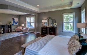 A large bedroom with seating area staged from the interior home design from CarrHomes in Hamilton.