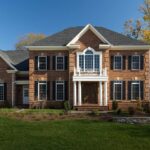 The outside of a CarrHomes designer home made with red brick and a second story balcony.